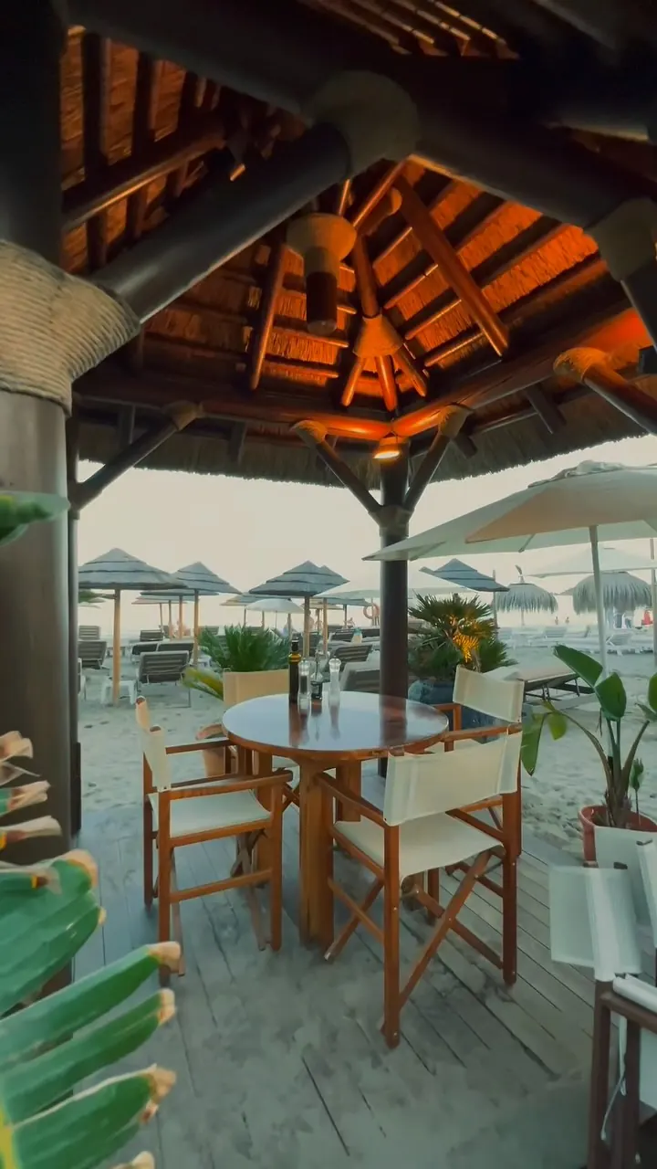 Mesa bajo un cenador de madera con vistas a la playa